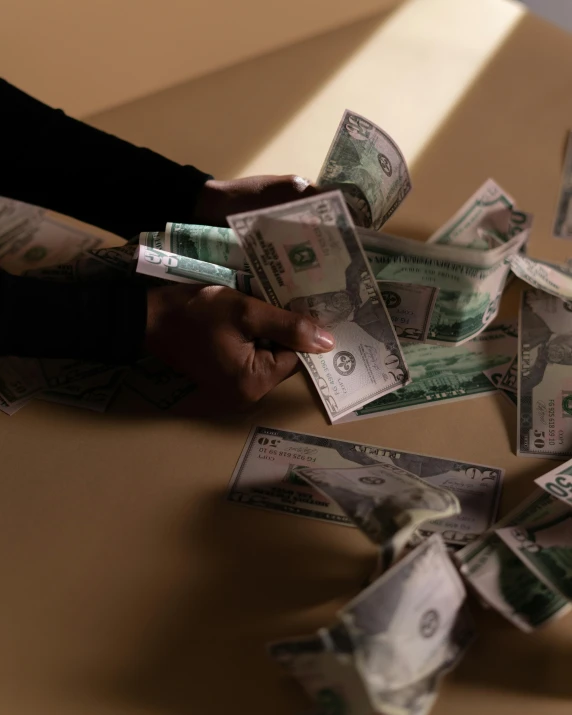 a person holding a bunch of money on top of a table, lgbtq, dimly lit scene, jemal shabazz, thumbnail