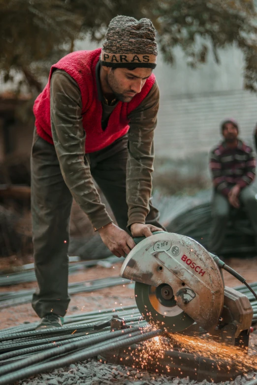 a man cutting metal with a circular saw, by Francis Helps, real life photo of a syrian man, worksafe. cinematic, brown, 🦑 design