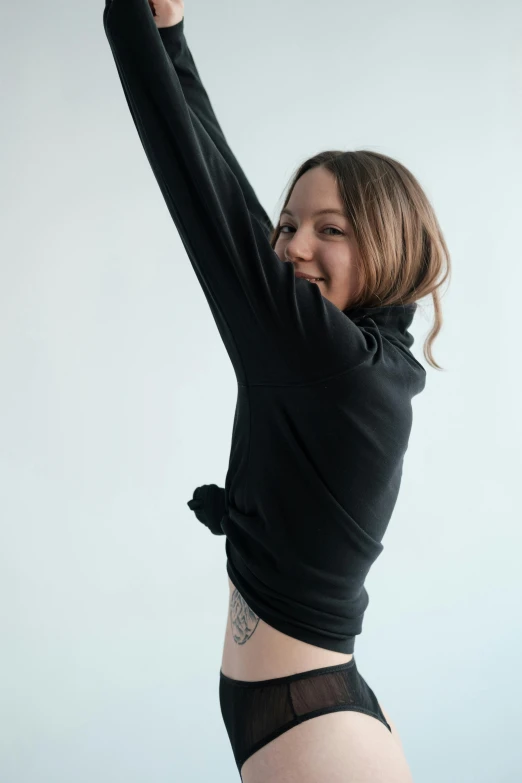 a woman stretching her arms in the air, an album cover, inspired by Elizabeth Polunin, unsplash, black turtle neck shirt, cheeky smile, pokimane, low quality photo