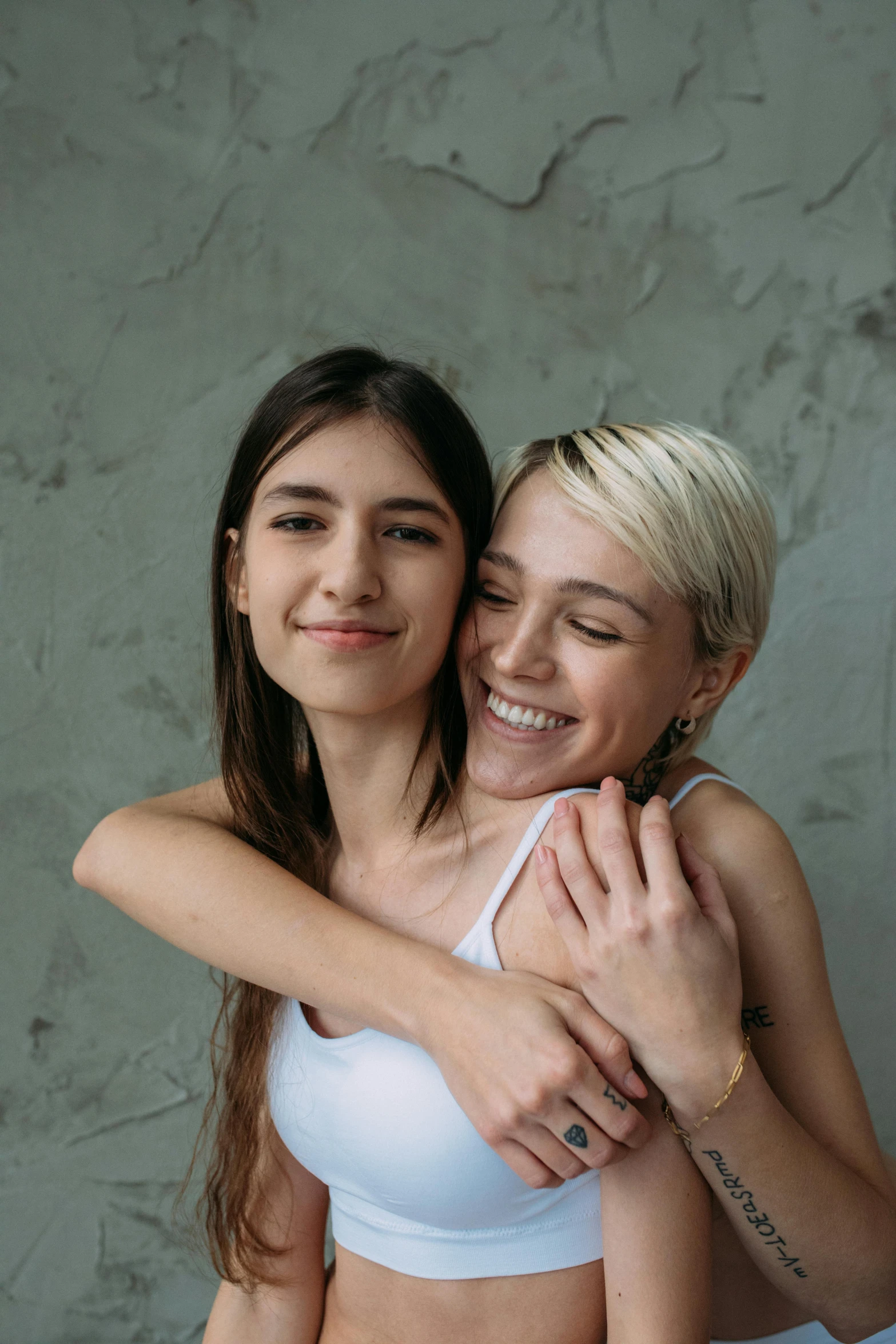 a couple of women standing next to each other, a photo, trending on pexels, hugging and cradling, girl with short white hair, young woman in her 20s, lesbian