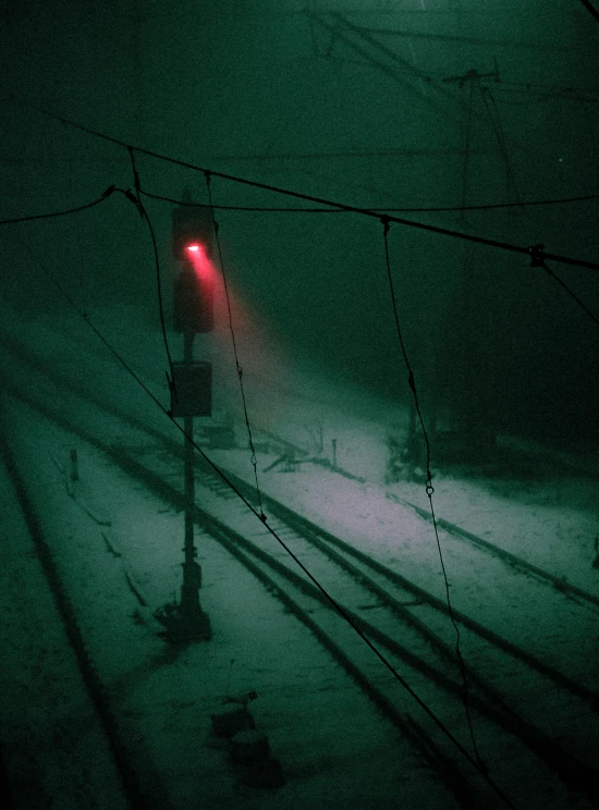 a red traffic light sitting on top of a snow covered ground, an album cover, inspired by Elsa Bleda, unsplash contest winner, inside an underwater train, eerie fog, wires, green light