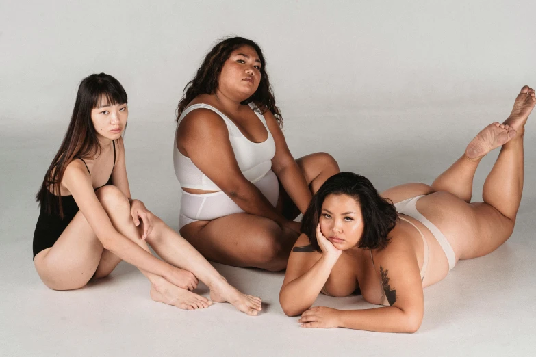 a group of women sitting on top of a white floor, inspired by Vanessa Beecroft, unsplash, bbw, half asian, wearing a white bikini, three women