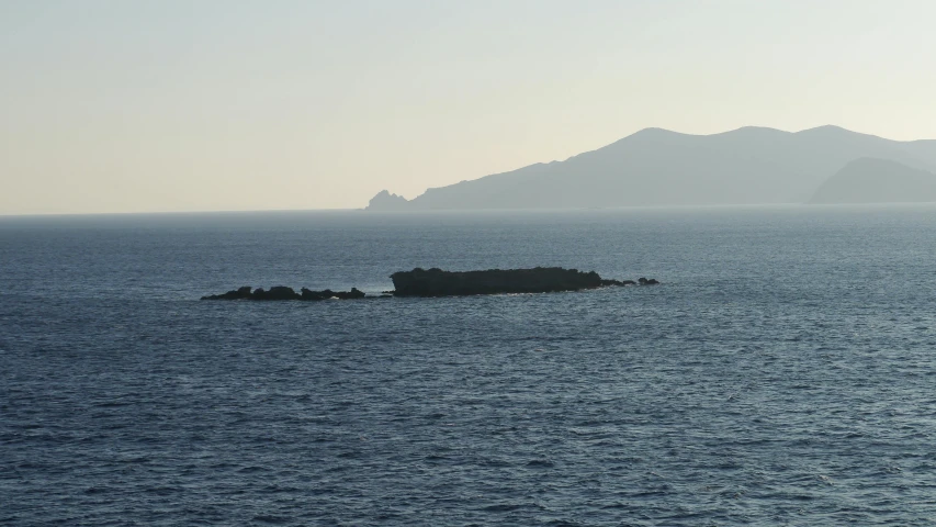 a small island in the middle of the ocean, a picture, by Exekias, seen from a distance, cycladic sculptural style, very low light, hziulquoigmnzhah