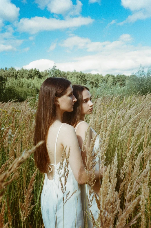 two women standing in a field of tall grass, an album cover, unsplash, conceptual art, anna nikonova aka newmilky, brunettes, twins, porcelain skin ”