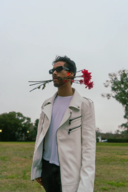 a man standing in a field with a flower in his mouth, an album cover, by Pablo Rey, unsplash, with sunglasses, slight overcast, tyler, alejandro