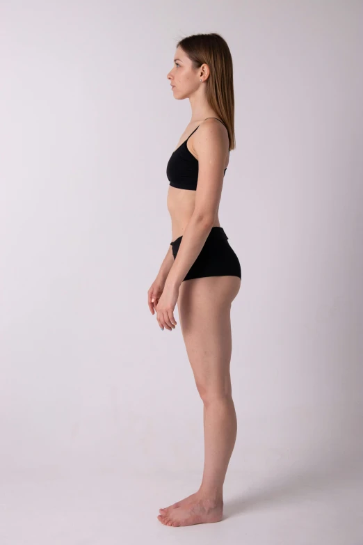 a woman in black shorts and a black bra top, standing posture, anorexic figure, female full-skin figure, full body photgraph