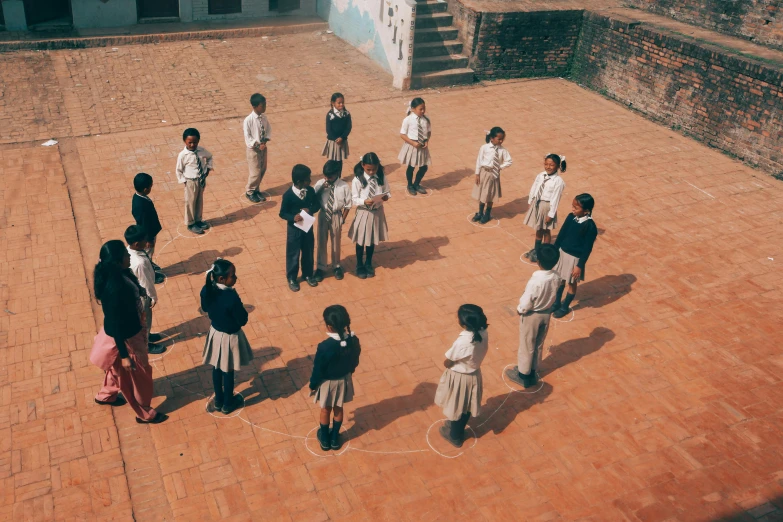 a group of children standing in a circle on a brick floor, inspired by Ke Jiusi, pexels contest winner, bengal school of art, overlooking, fzd school of design, on location, [ cinematic