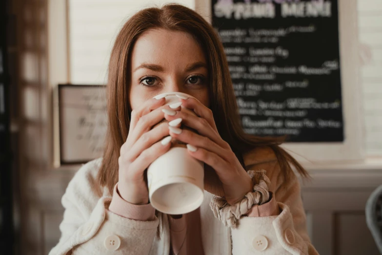 a woman sitting at a table drinking a cup of coffee, a portrait, trending on pexels, pokimane, extremely pale, cafe, 1 2 9 7