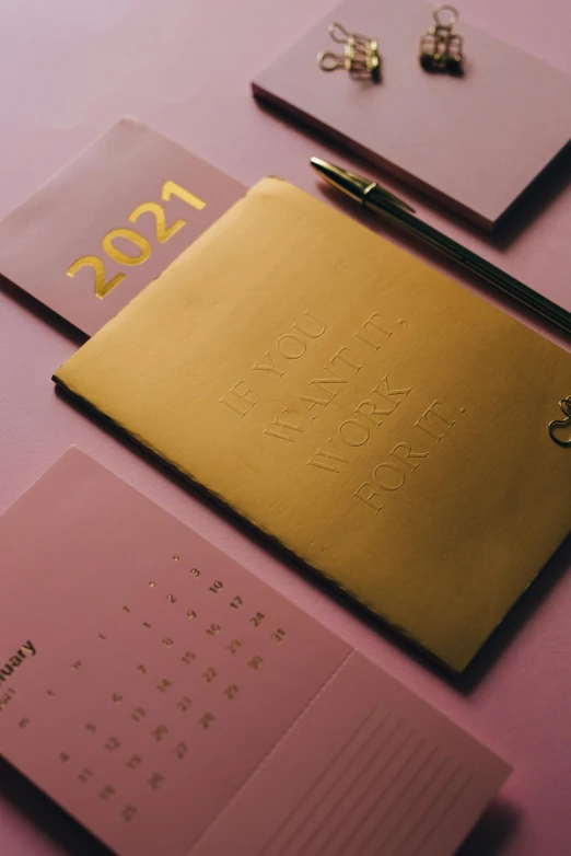 a couple of notebooks sitting on top of a table, gold and purple, thumbnail, female calendar, multiple stories