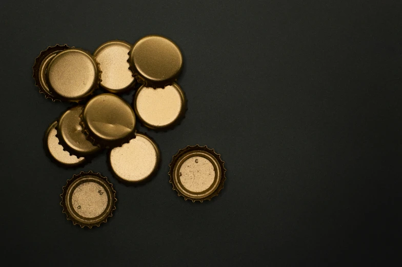 a bunch of bottle caps sitting on top of a table, pexels, gold black, plain background, product image, brown