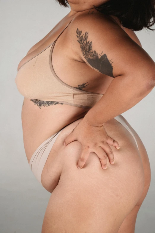 a woman in a bikini posing for a picture, an album cover, by Jessie Algie, unsplash, photorealism, curvy accentuated booty, heavy gesture style closeup, nonbinary model, her skin is light brown