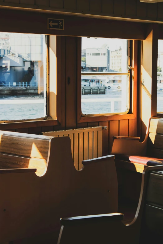 a couple of chairs sitting next to each other in front of a window, by Jan Tengnagel, unsplash, on a boat, brown and cream color scheme, tram, wooden trim