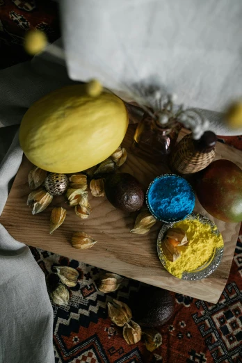 a wooden cutting board topped with fruit and nuts, a still life, unsplash, qajar art, yellow and blue and cyan, made of food, gourd, color photo