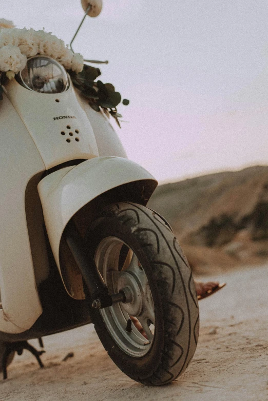 a white scooter parked on the side of a road, on the sand, ethereal details, an olive skinned, rugged details