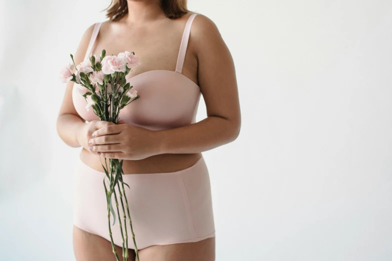a woman holding a bunch of pink flowers, by Matija Jama, trending on unsplash, white high waisted swimsuit, full figured, light blush, minimal pink palette