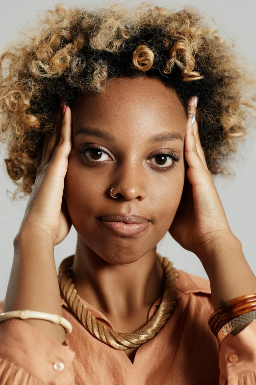 a woman with her hands on her head, short blonde afro, looking defiantly at the camera, maria borges, photo of a woman