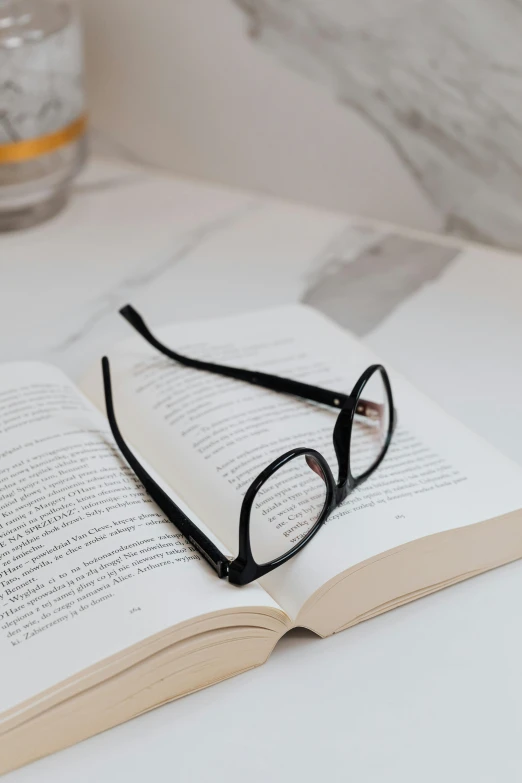a pair of glasses sitting on top of an open book, on white paper, up-close, minimalistic aesthetics, zoomed in
