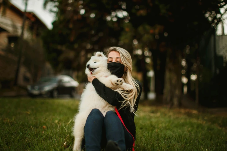 a woman sitting in the grass hugging a white dog, by Julia Pishtar, pexels contest winner, masked, avatar image, samoyed dog, casual photography