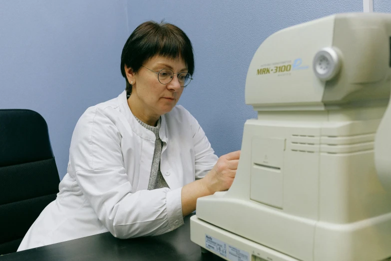 a woman sitting at a table in front of a machine, local conspirologist, profile image, neo kyiv, thumbnail