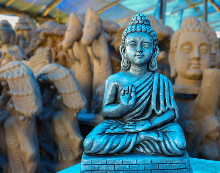 a statue of a buddha sitting on top of a table, a statue, by Sam Dillemans, pexels contest winner, cloisonnism, shades of blue and grey, temple fair, thumbnail, various posed