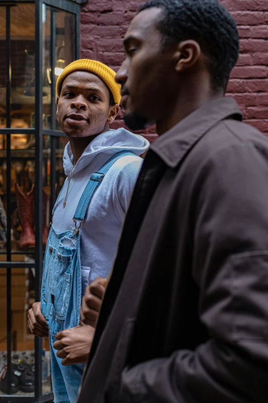 a group of men standing in front of a window, trending on pexels, visual art, new york alleyway, wearing a yellow hoodie, customers, ( ( theatrical ) )