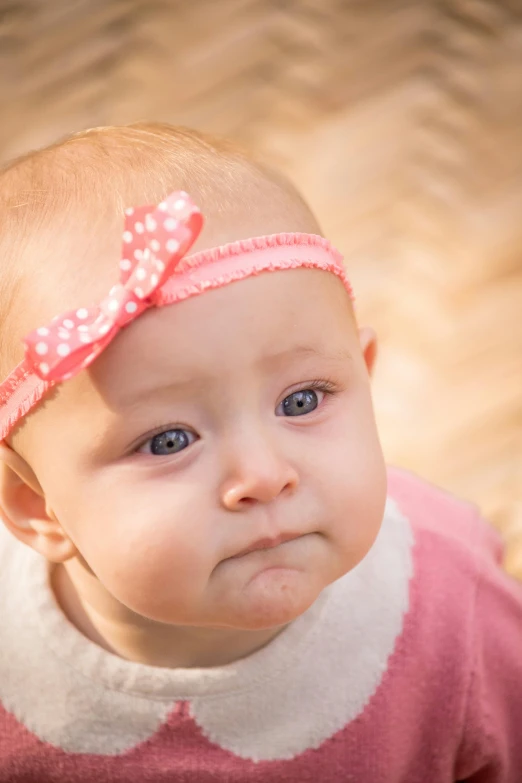 a close up of a baby with a bow on her head, a picture, by Julian Allen, shutterstock contest winner, beautiful grumpy girl, pink, disappointed, high resolution photo