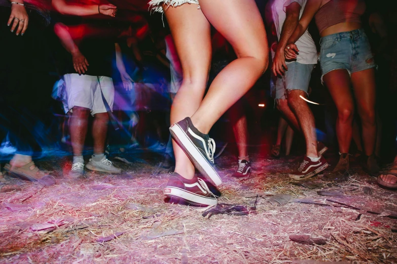 a woman standing on a skateboard in front of a group of people, an album cover, trending on pexels, happening, summer festival night, detailed legs, at a rave, saturday night in a saloon