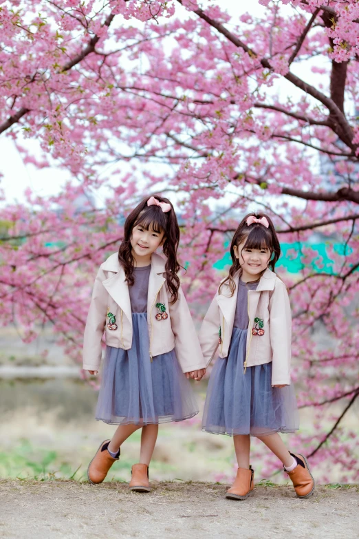 two little girls standing next to each other under a tree, a picture, instagram, shin hanga, 8 k ), spring season city, jacket, ((pink))