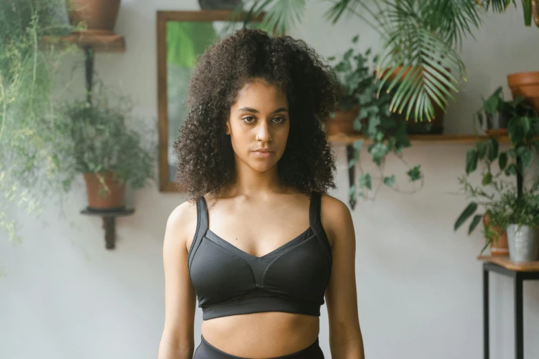 a woman in a black bra top sitting on a yoga mat, inspired by Louisa Matthíasdóttir, pexels contest winner, renaissance, mixed-race woman, with two front pockets, detailed sports bra, panel of black