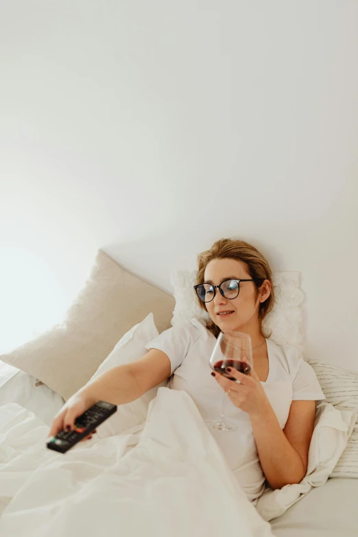 a woman sitting on a bed holding a remote control, pexels contest winner, enjoying a glass of wine, television sunglasses, gif, single