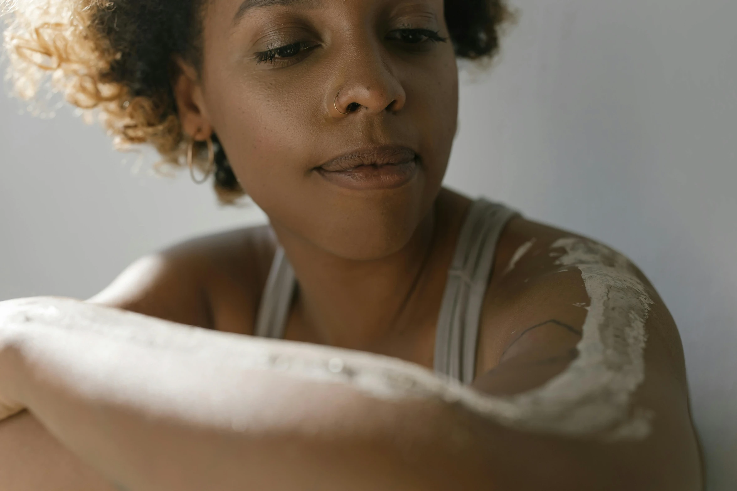 a close up of a woman with a brush in her hand, by Jessie Algie, trending on pexels, covered in white flour, looking her shoulder, mixed-race woman, looking from shoulder