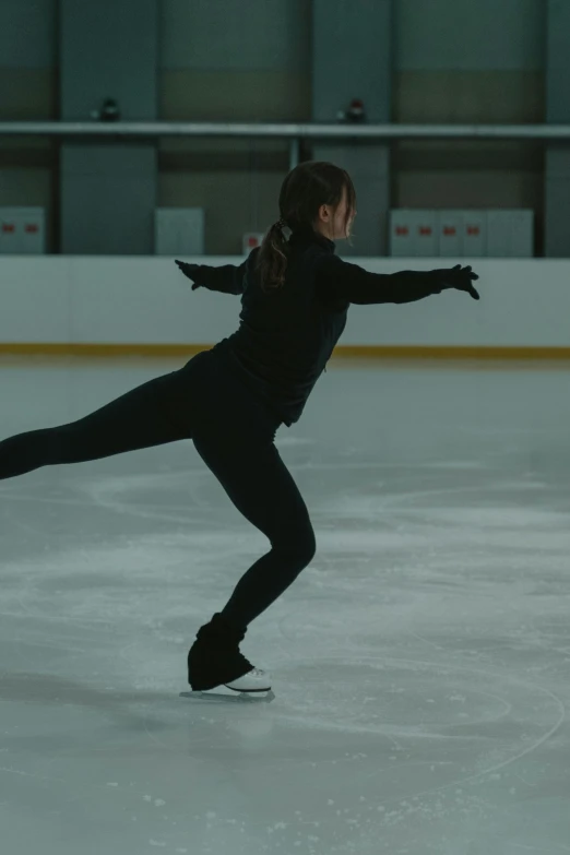 a female figure skating on an ice rink, inspired by Elizabeth Polunin, pexels contest winner, cinematic still frame, wearing a tracksuit, black, juno promotional image