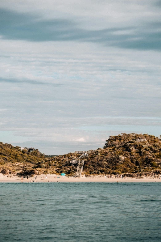 a small island in the middle of a body of water, unsplash, an australian summer landscape, crowded beach, rocky hills, chairlifts