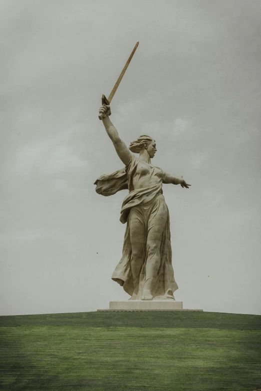 a statue of a woman holding a sword, by Attila Meszlenyi, unsplash, socialist realism, victorious on a hill, soviet architecture, storm, low quality photo