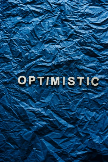 a blue crumpled paper with the word optimistic written on it, an album cover, trending on unsplash, profile picture, galactic, maritime, catholic