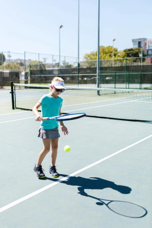 a woman standing on a tennis court holding a racquet, kids playing, soft surfaces, oceanside, square