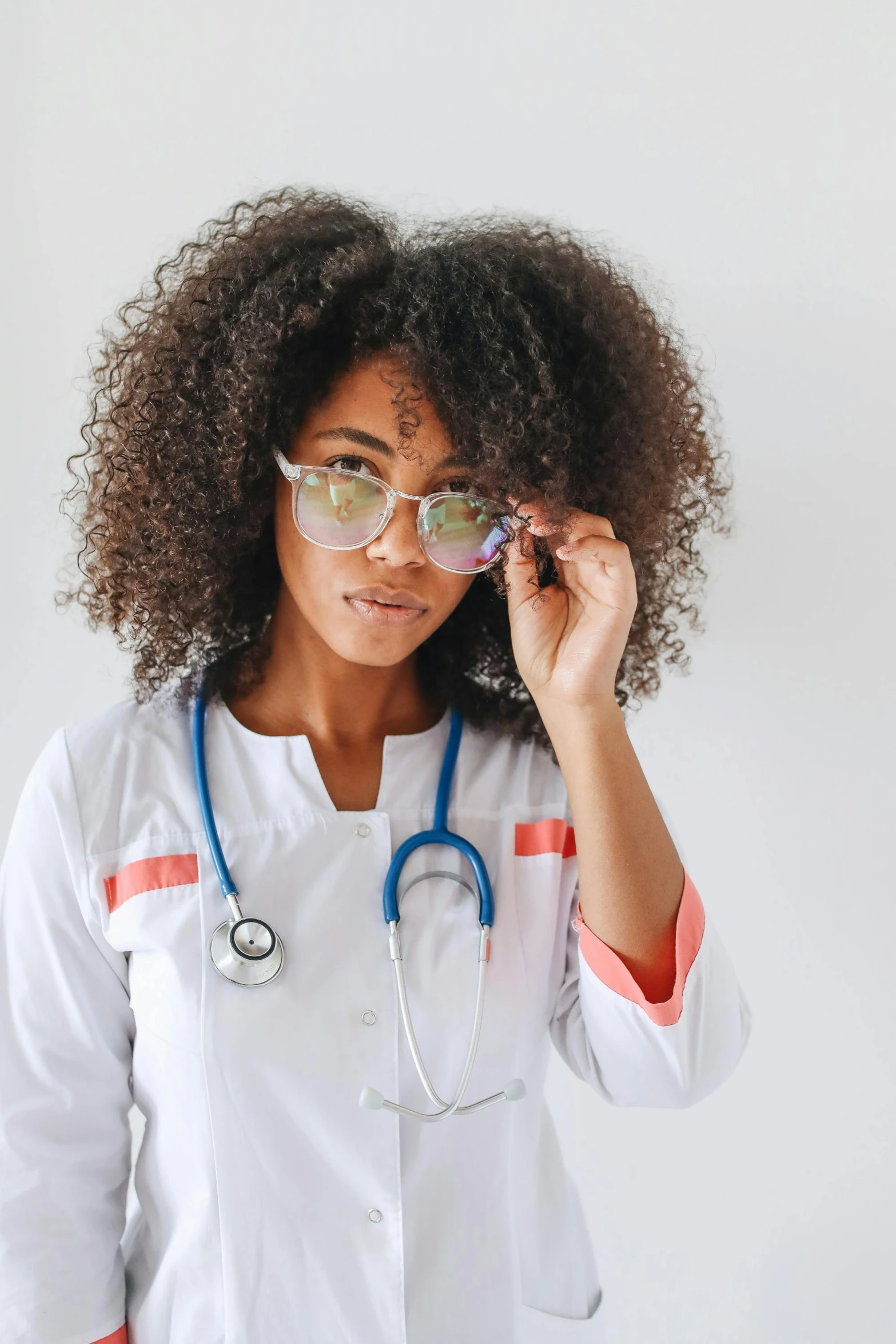 a woman with glasses and a stethoscope, inspired by Dr. Atl, trending on pexels, afrofuturism, wavy hair spread out, nurse uniform, instagram post, 2019 trending photo