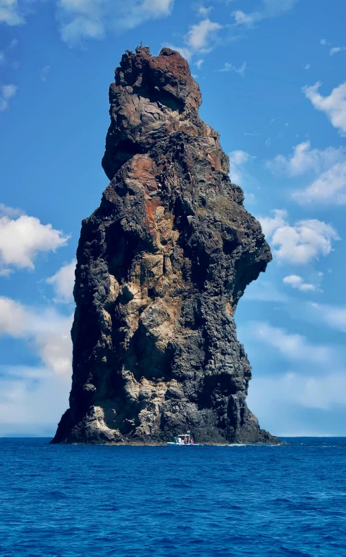 a rock formation in the middle of the ocean, towering high up over your view, 1km tall, vulcano, imposing