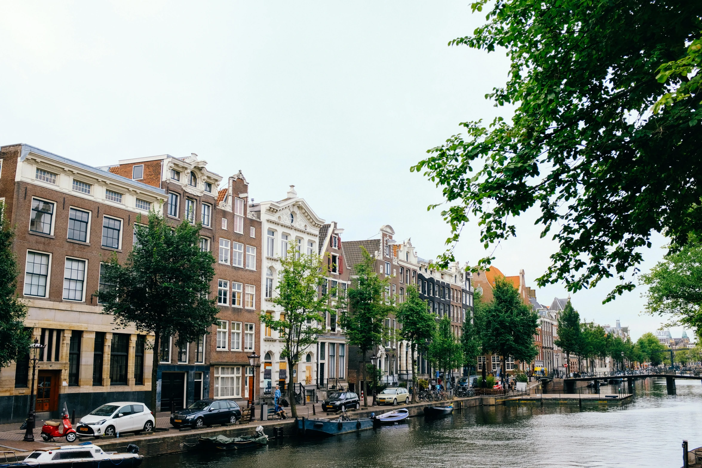 a canal filled with lots of boats next to tall buildings, by Maria van Oosterwijk, pexels contest winner, neoclassicism, white houses, thumbnail, greenery, rem koolhaas