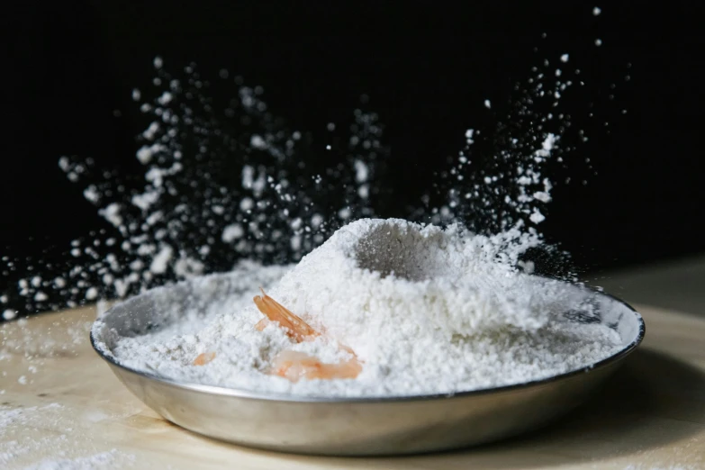 a bowl filled with powder on top of a wooden table, a still life, trending on unsplash, process art, shrimp, pastry, background image, slow - mo high speed photography