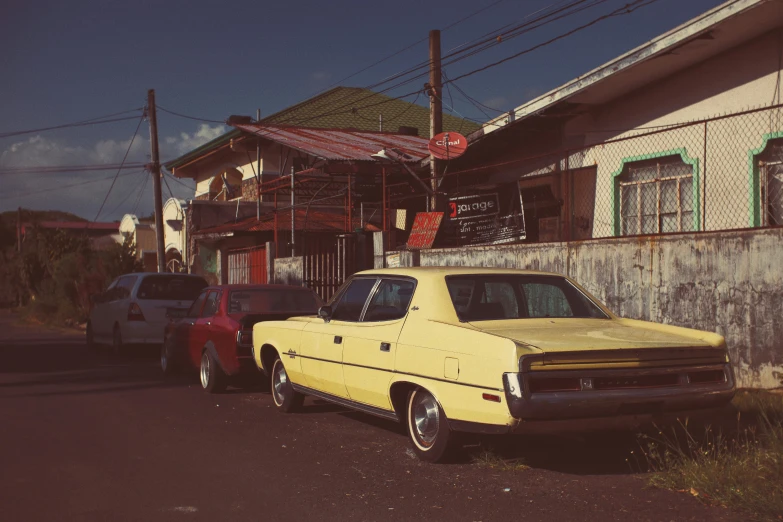 a yellow car parked in front of a building, by Pamela Ascherson, pexels contest winner, 70s photo, reunion island, faded red and yelow, in an american suburb