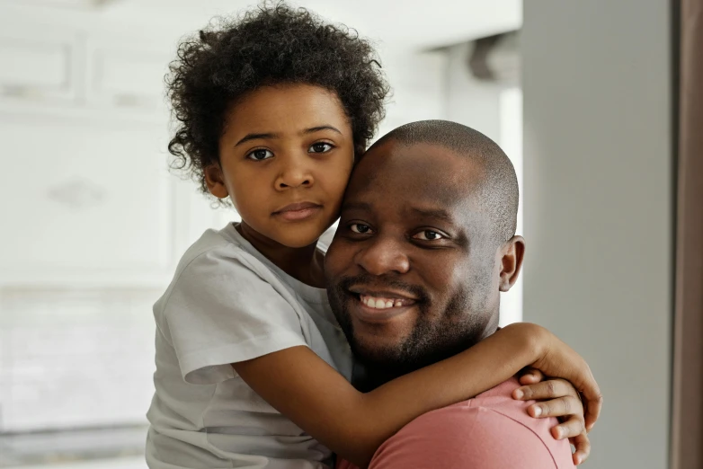 a man holding a little girl in his arms, pexels contest winner, hurufiyya, dark skin tone, looking confident, hugging each other, gray men