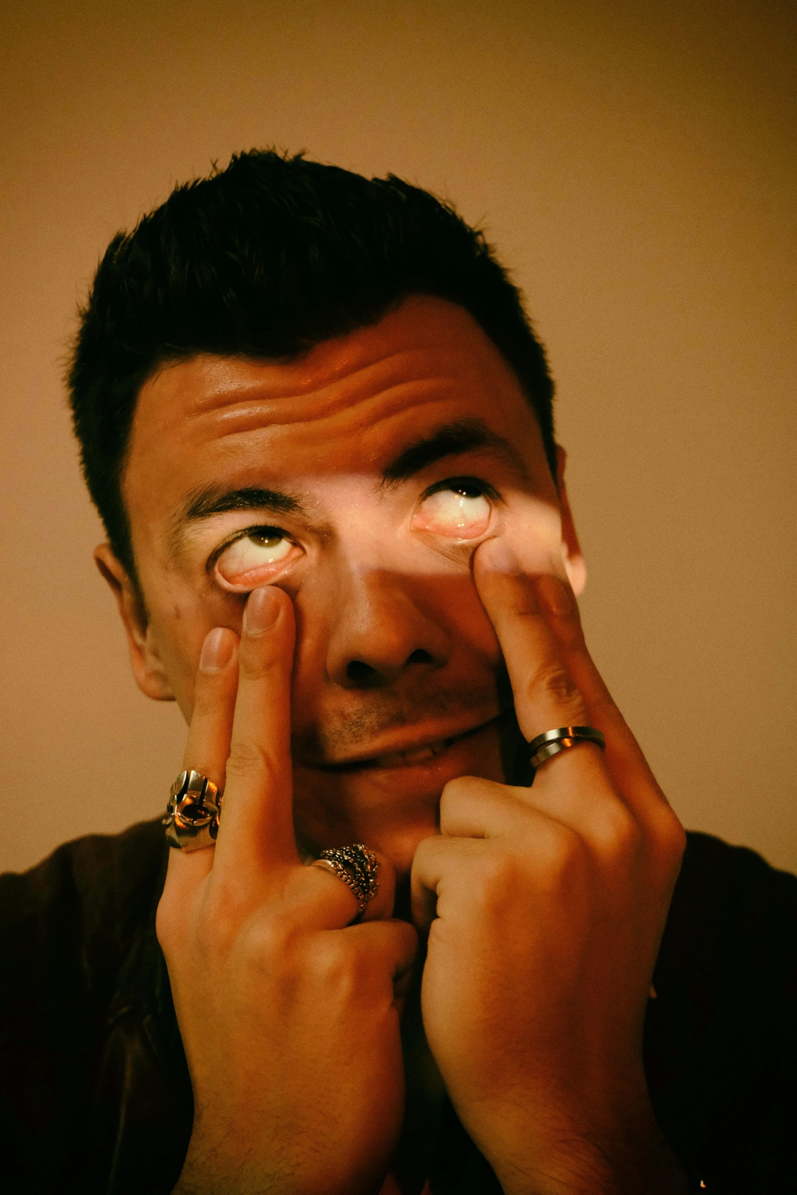 a man covering his eyes with his hands, an album cover, inspired by Taro Yamamoto, trending on pexels, photorealism, rick astley, glowing (((white laser))) eyes, sits on a finger, joe rogan