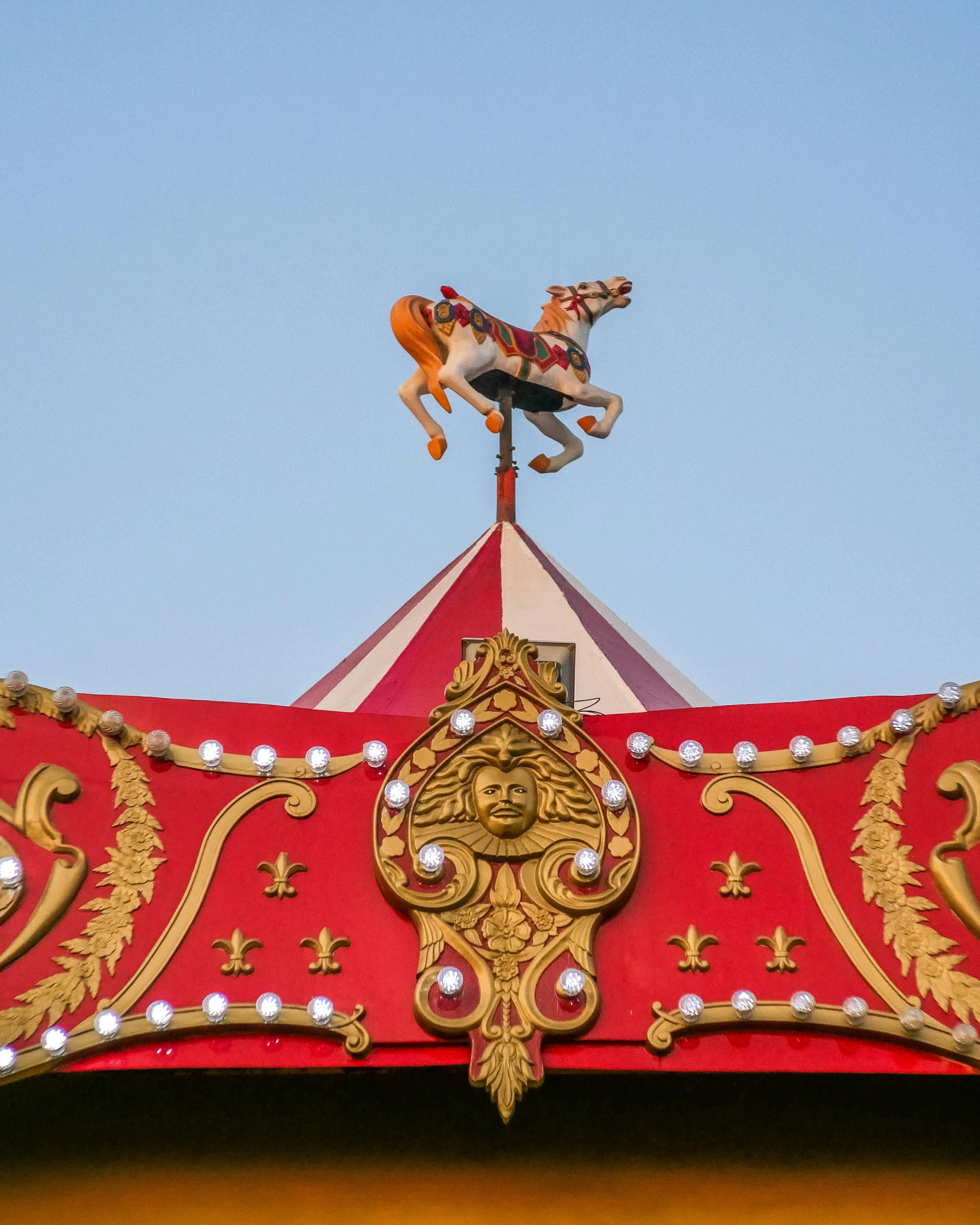 a red and gold carousel with a horse on top, trending on unsplash, shot from roofline, ilustration, high detail photo, cover image