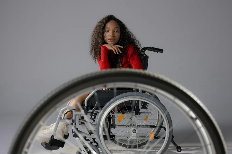 a woman is sitting in a wheel chair, an album cover, trending on pexels, hurufiyya, avatar image, model posing, b - roll, professional image
