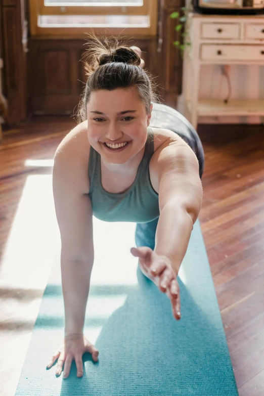 a woman doing a yoga pose on a yoga mat, a portrait, by Jessie Algie, pexels contest winner, smiling, bending down slightly, promo image, lower quality
