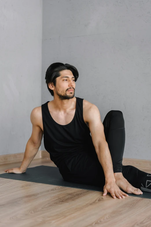 a man sitting on a yoga mat in a room, unsplash, shin hanga, wearing black tight clothing, arms to side, yukito kishiro, ad image