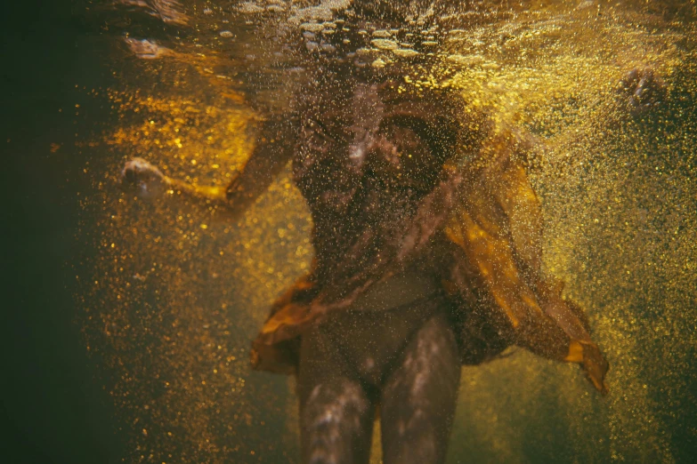 a person swimming in a body of water, inspired by Brooke Shaden, unsplash contest winner, draped in gold, dust and particles, 2 0 0 0's photo, full frame image