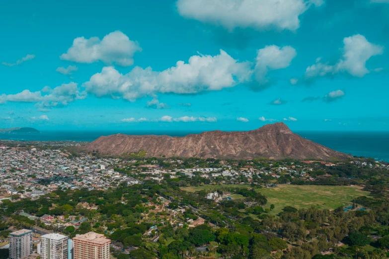 a city with a mountain in the background, pexels contest winner, hawaii, background image, aerial view of an ancient land, blue skies