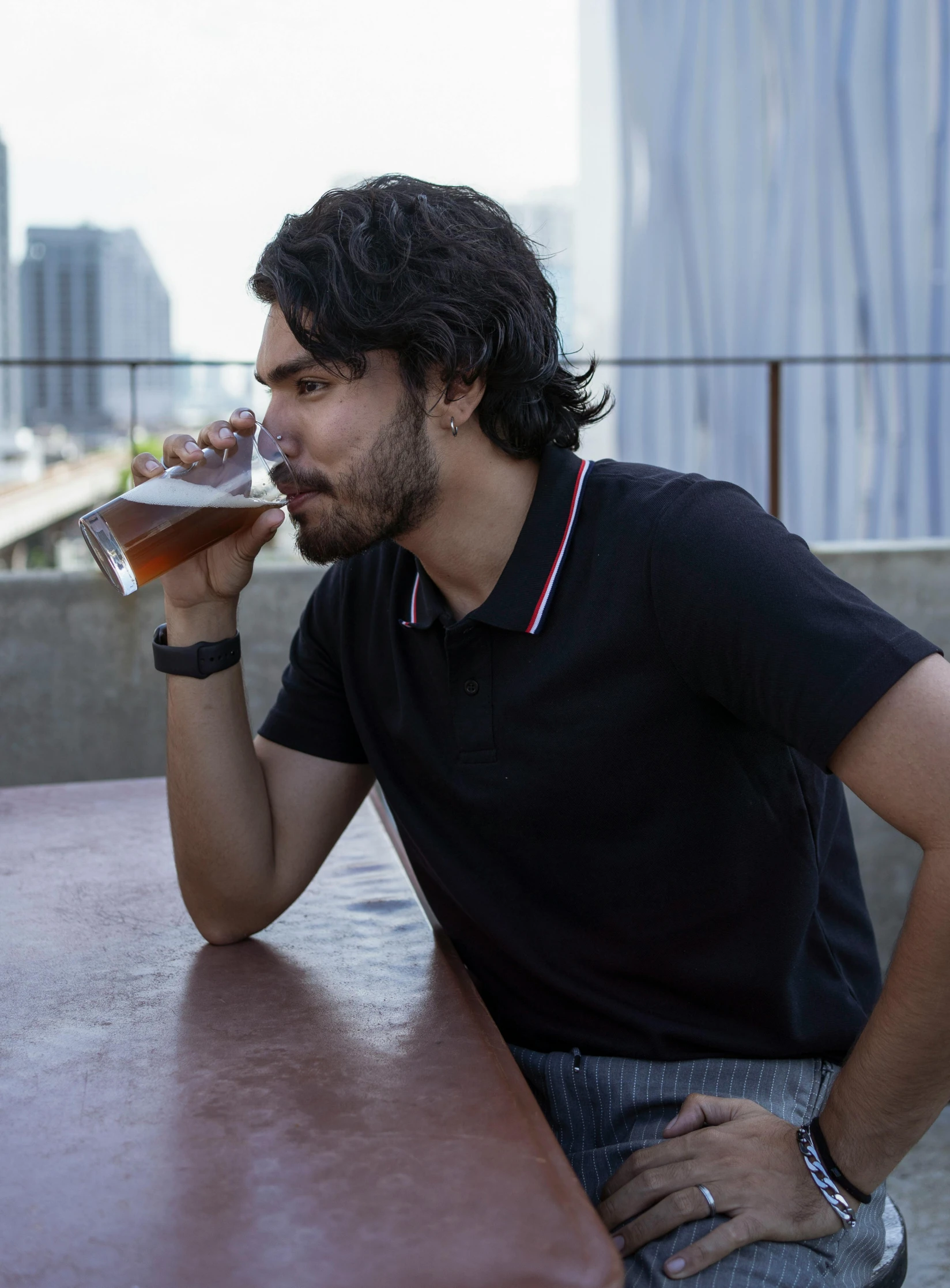 a man sitting at a table drinking from a glass, wearing polo shirt, jayison devadas, rooftop, profile image